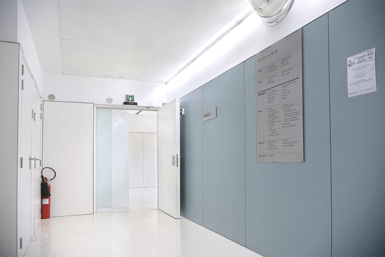 Puertas cortafuegos de dos hojas en un pasillo de tránsito continuo, con cierre automático.